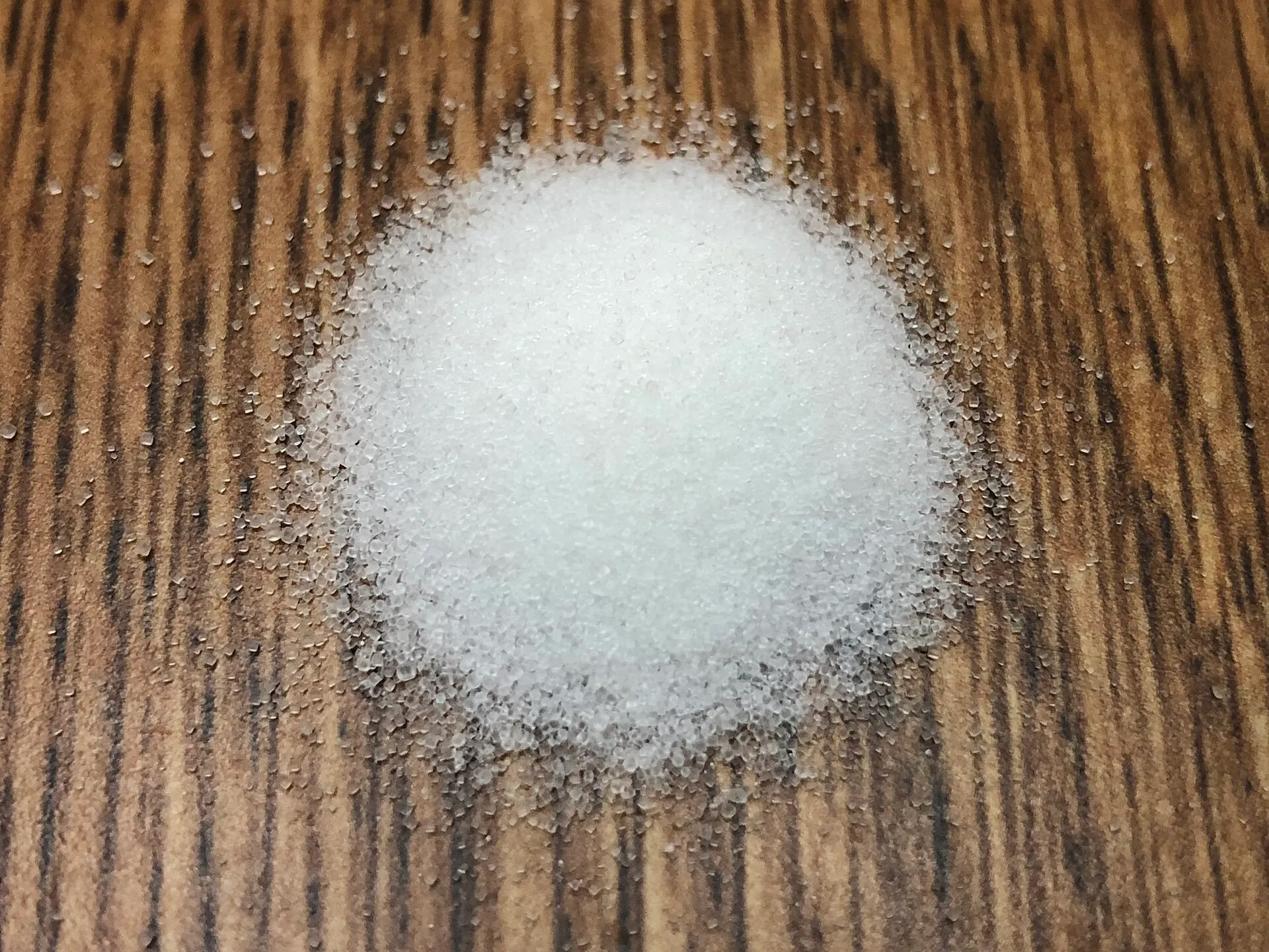 A small pile of table salt on a wood surface